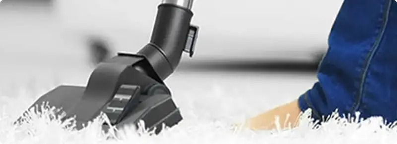 Close-up of a professional vacuuming a white carpet in Bedford.
